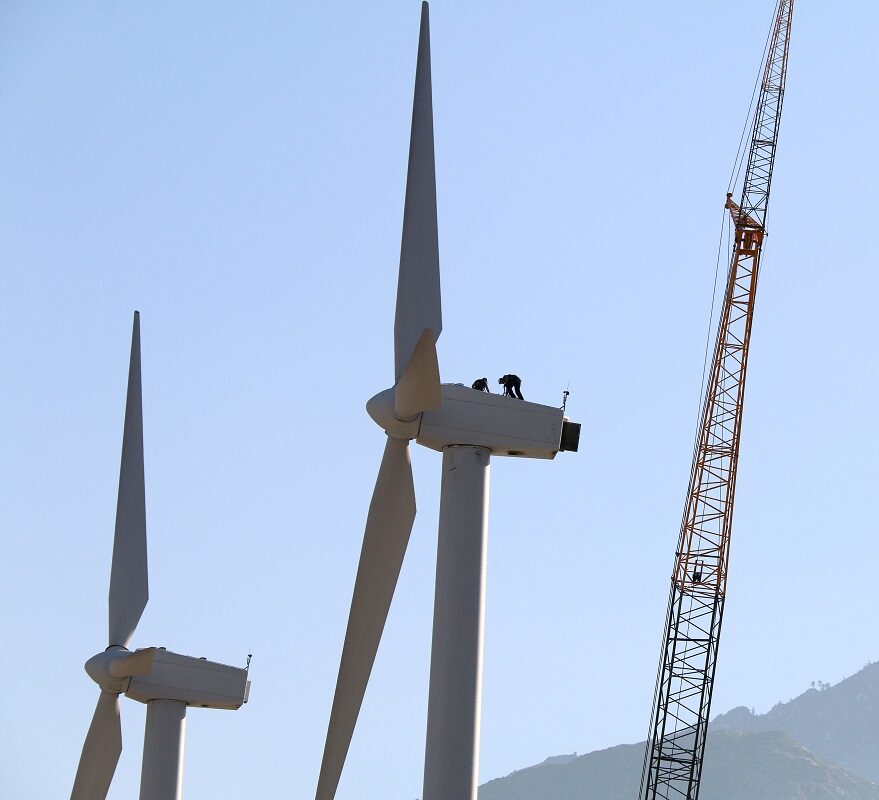 2 workers on top of wind turbine in a mountain desert area