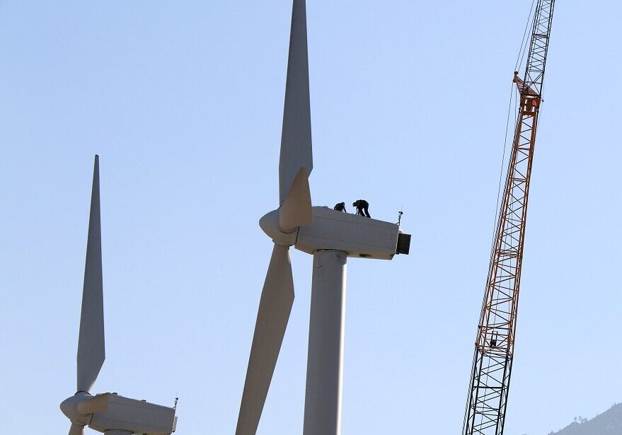 2 workers on top of wind turbine in a mountain desert area